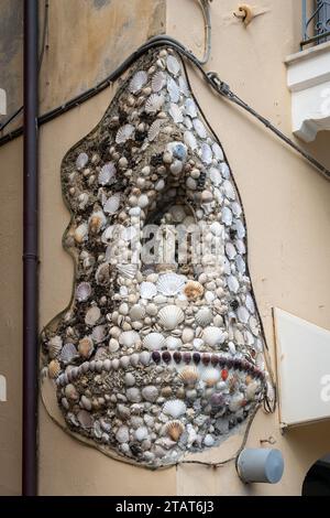 Sanctuaire votif couvert de coquillages dédiés à la Vierge Marie et à l'enfant Jésus sur un coin de rue dans la ville côtière, finale Ligure, Savone, Ligurie Banque D'Images