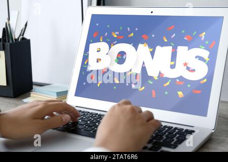 Gain de bonus. Femme utilisant un ordinateur portable à table, gros plan. Illustration de la chute de confettis et mot sur l'écran de l'appareil Banque D'Images