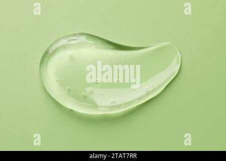 Frottis de gel cosmétique transparent sur fond vert clair, vue de dessus Banque D'Images