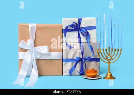 Cadeaux pour la célébration Hanukkah, menorah et beignet sur fond de couleur Banque D'Images