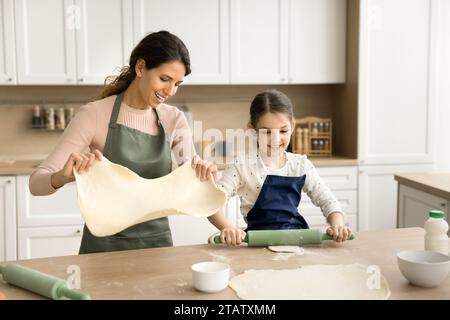 Heureuse fille d'enfant aidant maman à cuire, préparant des tartes maison Banque D'Images