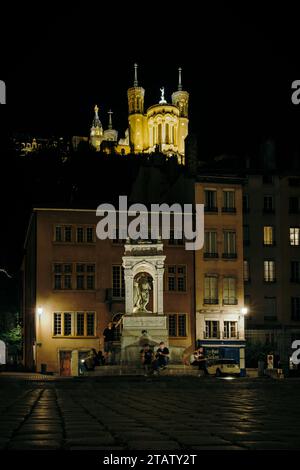 Vue de nuit sur la basilique Fourvière depuis la place Saint Jean et sa fontaine située dans le Vieux Lyon, la vieille ville de Lyon (France) Banque D'Images