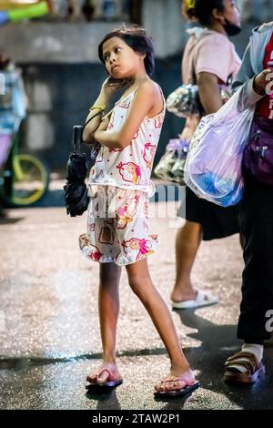 Une jolie jeune fille philippine attend sa famille devant l’église Santo Nino de Tondo à Manille, aux Philippines. Banque D'Images