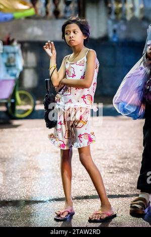 Une jolie jeune fille philippine attend sa famille devant l’église Santo Nino de Tondo à Manille, aux Philippines. Banque D'Images