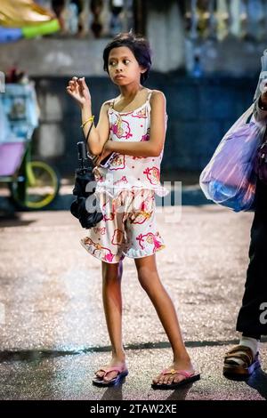 Une jolie jeune fille philippine attend sa famille devant l’église Santo Nino de Tondo à Manille, aux Philippines. Banque D'Images