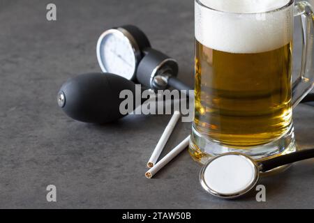 Verre de bière, cigarettes et moniteur de pression artérielle, abus d'alcool, nicotine, concept d'hypertension Banque D'Images