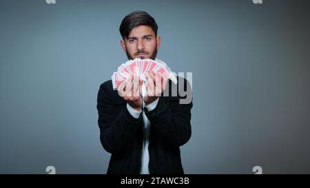 Jeune homme tenant des cartes sur fond gris, Focus sur les cartes, cartes à jouer Banque D'Images