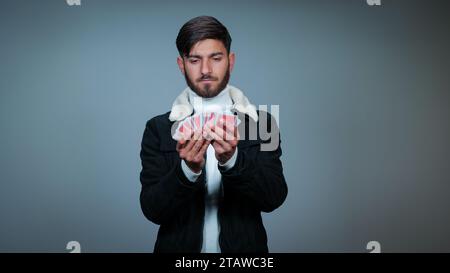 Jeune homme tenant des cartes sur fond gris, Focus sur les cartes, cartes à jouer Banque D'Images