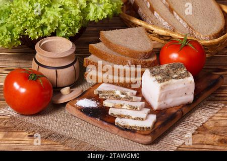 Graisse de porc salée avec condiments et légumes, petit déjeuner ukrainien traditionnel. Salo blanc tranché ou lard dans un style campagnard. Banque D'Images