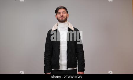 Un beau jeune homme debout heureux sur un fond gris. Banque D'Images