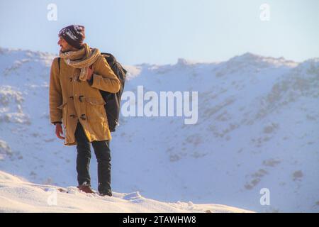 Un jeune homme randonnant au sommet des montagnes enneigées pendant la saison hivernale | randonnée hivernale | randonnée dans la neige. Banque D'Images