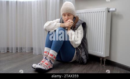 Femme bouleversée essayant de se réchauffer dans un appartement froid sans chauffage. Concept de crise énergétique, factures élevées, système de chauffage cassé, économie et économie Banque D'Images