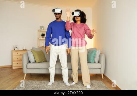 couple noir entièrement immergé dans le jeu de réalité virtuelle à la maison Banque D'Images