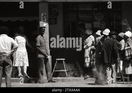 Apartheid Afrique du Sud 1987, 1 sur 3 photos. Les acheteurs blancs ont été prioritaires par les gardes de police tandis qu'une longue file d'attente de 30 à 40 acheteurs noirs attendaient dehors. Hekpoort, Magaliesberg, Afrique du Sud. De la collection - Afrique du Sud années 1980 - Archives photographiques Don Minnaar Banque D'Images