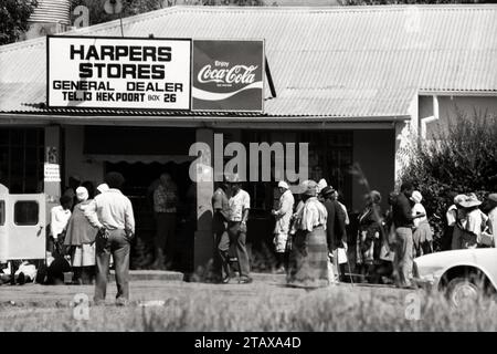 Apartheid Afrique du Sud 1987, 1 sur 3 photos. Les acheteurs blancs ont été prioritaires par les gardes de police tandis qu'une longue file d'attente de 30 à 40 acheteurs noirs attendaient dehors. Hekpoort, Magaliesberg, Afrique du Sud. De la collection - Afrique du Sud années 1980 - Archives photographiques Don Minnaar Banque D'Images