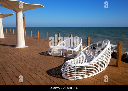 Mobilier moderne en rotin blanc pour créer une piscine extérieure dans le salon en bord de mer. Piscine luxueuse avec chaises longues blanches à la mode sur le beac Banque D'Images