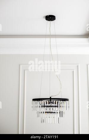 Plafonnier dans interior.Chandelier en verre, cristal et métal noir pend dans la chambre. Éclairage. Banque D'Images