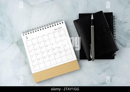 Calendrier de mars 2024, stylo et organisateur personnel sur bureau en marbre plat Banque D'Images