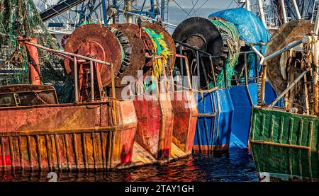 Chalutiers de pêche commerciaux colorés et rouillés amarrés. Les filets sont sur des bobines sur la poupe. Banque D'Images