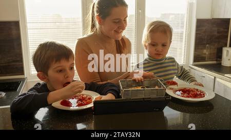 Jeune mère nourrissant ses fils avec de la soupe dans la cuisine. Nourriture domestique, cuisine à la maison, nutrition saine des enfants Banque D'Images