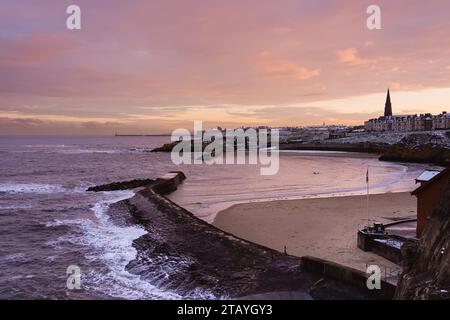 Vue sur le port de Cullercoats depuis la digue de Cullercoats Watch House, au coucher du soleil avec les vagues qui s'écrasent sur la jetée victorienne. Banque D'Images