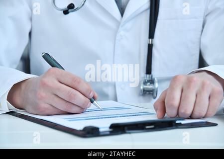La main du médecin remplit la liste des antécédents du patient dans le presse-papiers. Concept de santé et de médecine. Banque D'Images