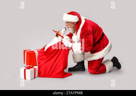 Père Noël avec chien mignon Jack Russell Terrier en cornes de renne et sac sur fond gris Banque D'Images