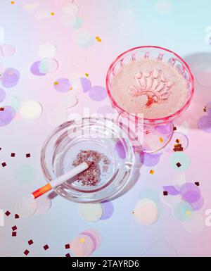 Une cigarette dans un cendrier, champagne pétillant dans un verre, confettis pastel dans une scène de fête sur un fond violet pastel de rêve Banque D'Images