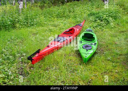 Deux kayaks - rouge et vert sont sur l'herbe verte Banque D'Images