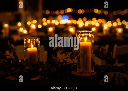 Une table romantique avec des bougies allumées et de la verdure lors d'un événement nocturne. Les bougies créent une atmosphère chaleureuse et intime, tandis que la verdure ajoute Banque D'Images