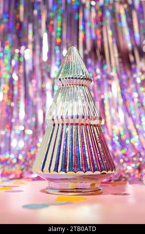 Un arbre de Noël coloré iridescent sur un fond de rideau de Tinsel Foil Party Banque D'Images
