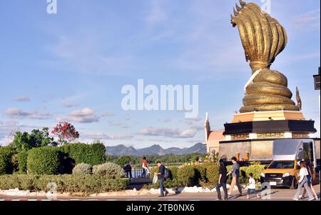 Le monument Naga, construit en 2016 à Nakhon Phanom, en Thaïlande, présente une grande statue de serpent Naga en laiton à 7 têtes face au nord de l'autre côté du Mékong. Coûtant 9 millions de bahts, la sculpture mesure 4,49 mètres de large, 10,90 mètres de haut et pèse 9 tonnes. Nommée Phaya si Sattanakharat, elle est considérée comme la plus grande sculpture Naga en laiton du nord-est de la Thaïlande. Le Naga, au cœur de la mythologie thaïlandaise et du bouddhisme, a joué un rôle crucial dans la protection du Bouddha pendant l'illumination, comme dans l'histoire de Mucalinda, le Naga à 7 têtes. Banque D'Images