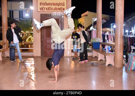 De jeunes garçons et filles athlétiques prennent part à une fête de groupe de danse, ici un adolescent de 15 ans fait de la danse athlétique à l'envers, à Nakhon Phanom, Isaan, Thaïlande, Asie du Sud-est. Le lieu est Vietnam Memorial Clock Tower , une tour d'horloge construite par les Vietnamiens pour montrer la bonne relation entre la Thaïlande et le Vietnam lorsque les immigrants vietnamiens ont déménagé à Nakhon Phanom pour vivre dans cette province. Le lieu est en plein air et gratuit pour tout le monde à utiliser. Banque D'Images