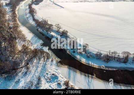 Vol au-dessus de la nature hivernale avec vue sur un lit de rivière incurvé entouré de champs Banque D'Images