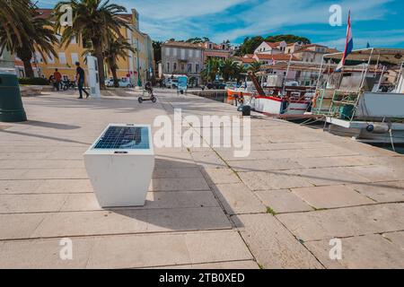 Banc équipé de panneaux solaires sur une plage à mali losinj, utilisé pour charger les téléphones portables et autres appareils alimentés par batterie en utilisant la puissance du soleil. Ur Banque D'Images