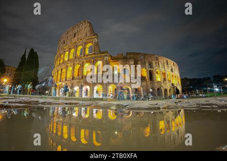 Vue nocturne du colisée à Rome, ciel bleu au-dessus du grand amphithéâtre célèbre. Réglage d'automne, reflet visible dans la flaque d'eau et Banque D'Images