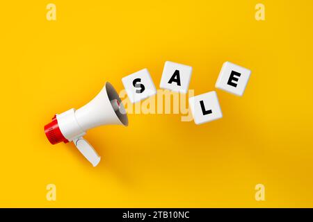 Concept de marketing d'affaires d'annonce de remise de prix. Le mot sale est écrit sur des blocs blancs avec un mégaphone sur fond jaune. Rendu 3D. Banque D'Images