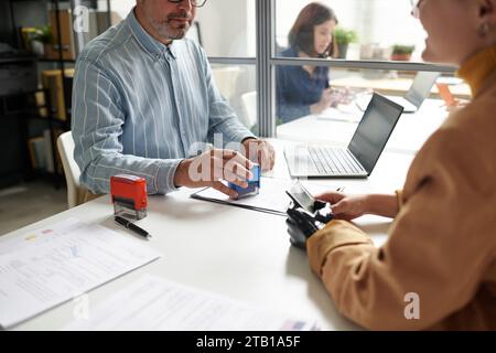 Directeur du centre de visa ayant une réunion avec le client, il parle à la femme et met des timbres sur les documents Banque D'Images