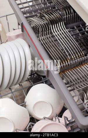 Lave-vaisselle intégré ouvert avec couverts propres, vaisselle, assiettes dans une cuisine moderne blanche. vue de dessus Banque D'Images