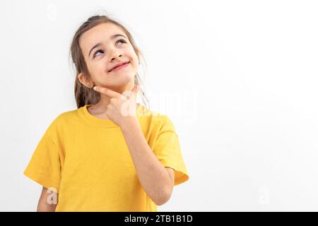 Drôle petite fille regarde slyly sur un fond blanc isolé. Banque D'Images