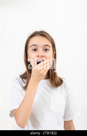 Adolescente surprise couvrant sa bouche avec sa main isolée sur blanc. Banque D'Images