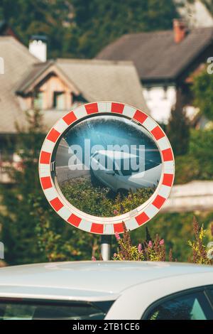 Miroir de circulation avec un reflet de voiture blanche dans le village alpin pittoresque en été, mise au point sélective Banque D'Images