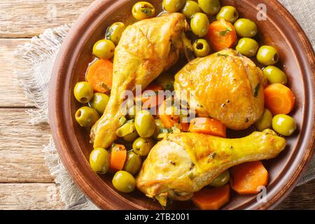 Tajine zitoune est un mélange de poulet de légumes ad épices cuisine en gros plan sur table en bois. Vue de dessus horizontale Banque D'Images