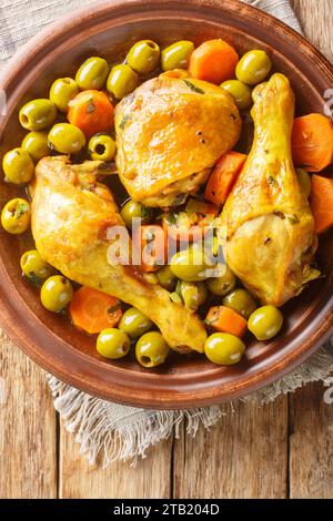 Tajine Zitoune est un plat de ragoût algérien qui se compose de poulet cuit avec des carottes et des olives vertes en utilisant des épices nord-africaines en gros plan sur ta en bois Banque D'Images