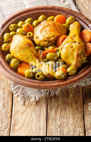 Tajine Zitoune est un plat de ragoût algérien qui se compose de poulet cuit avec des carottes et des olives vertes en utilisant des épices nord-africaines en gros plan sur ta en bois Banque D'Images