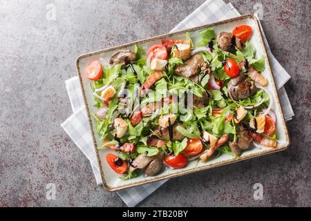 Salade de légumes frais avec foie de poulet grillé et bacon gros plan sur l'assiette sur la table. Vue de dessus horizontale Banque D'Images