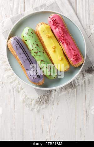 Belle délicieux eclairs français ensemble avec décor crème original sur plaque sur fond en bois. Vue verticale de dessus Banque D'Images