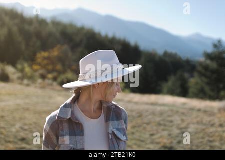 Portrait d'une belle fille dans un chapeau à la mode près des montagnes. Banque D'Images