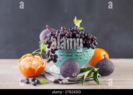 Raisin, mandarine et figues fruits dans un bol bleu sur une table en bois, fond de nourriture saine. Régime alimentaire, fructose et concept vitaminique Banque D'Images