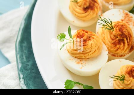 Œufs farcis ou dévorés avec paprika et persil sur une assiette bleue pour la table de pâques. Plat traditionnel pour Pâques. Alimentation saine pour le petit déjeuner. Top vie Banque D'Images